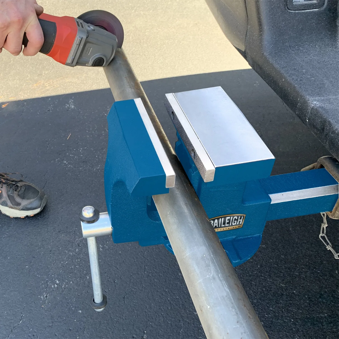 Baileigh 6" Heavy Duty Hitch Vise BV-6HV 1227908 in use clamping metal stock, demonstrating stable holding power and portable jobsite versatility for fabrication and repair tasks.