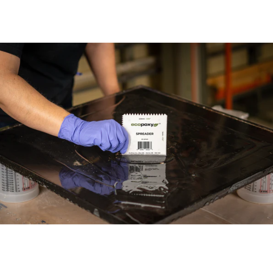 Ecopoxy V-Notched EcoPoxy Spreader (Pack of 36) EP-SPV01-36X being used by gloved hands to evenly spread epoxy resin across a flat surface