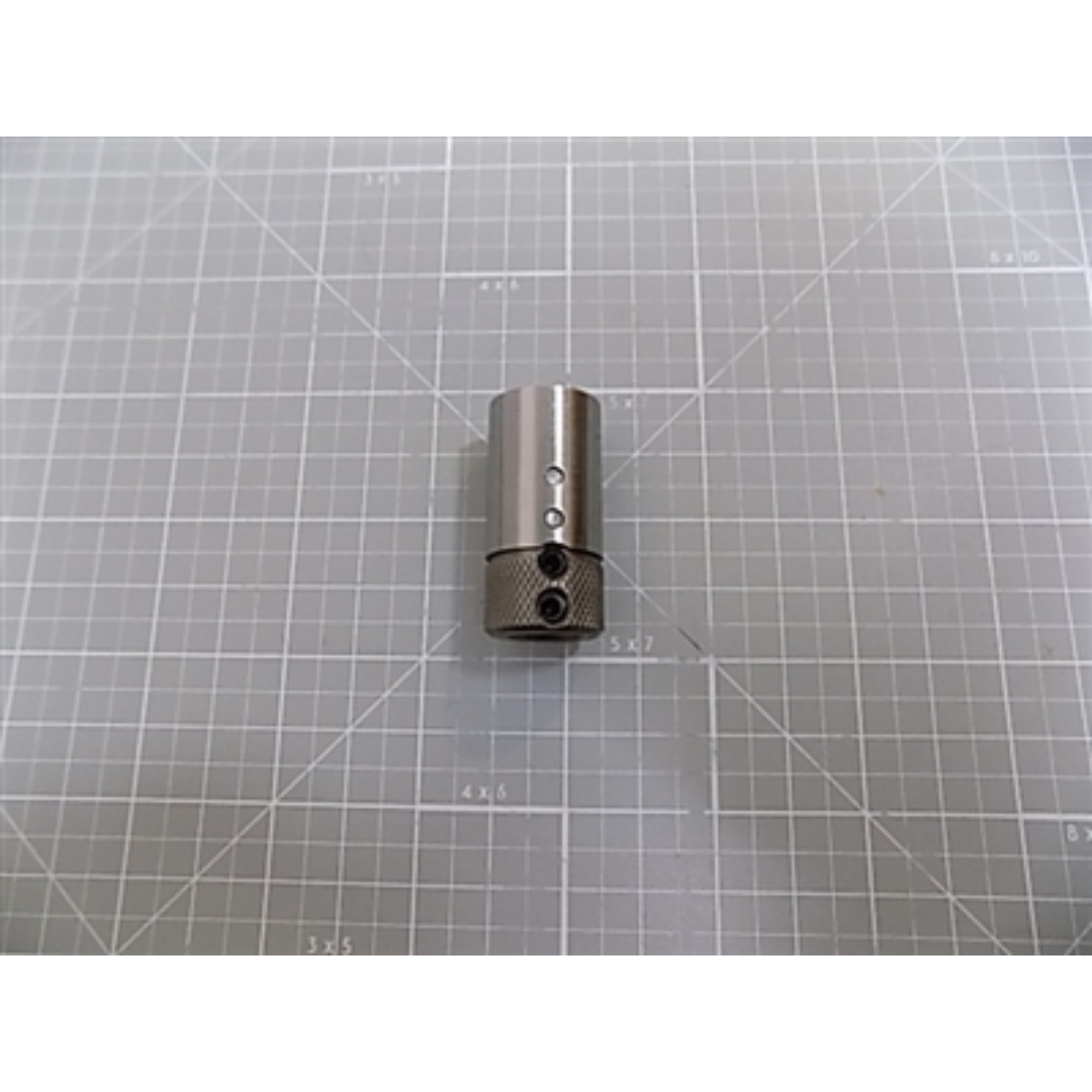 Maggi Quick Change Bit Adaptor 36000061 precision metal adaptor displayed on a cutting mat with grid background for accurate scale reference