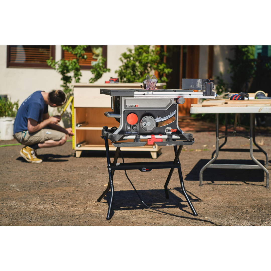 SawStop Compact Table Saw Folding Stand CTS-FS supporting a compact table saw in an outdoor work environment, demonstrating portability and convenient setup for construction projects.
