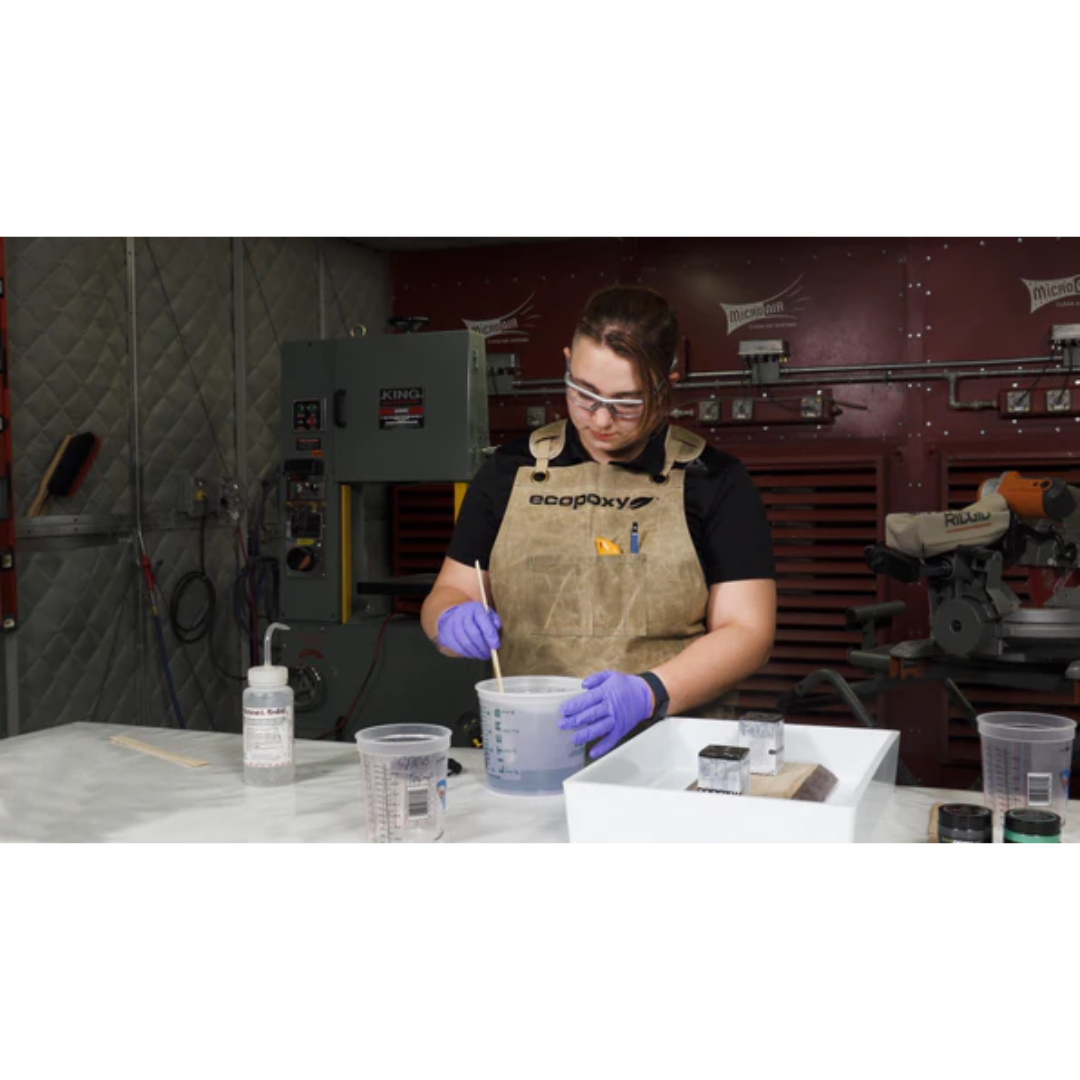 Woodworker wearing the Ecopoxy Canvas Apron EPAPR10-CV while mixing epoxy resin in a professional workshop.